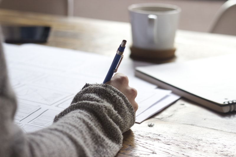 A student studying at a tidy desk with an open notebook and laptop