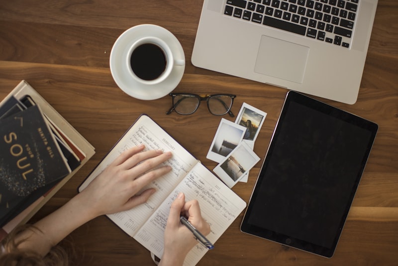 A person at a desk pausing over study materials and a laptop